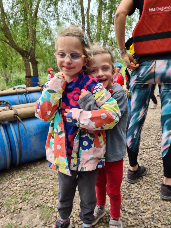 Raft-Building-1-scaled-e1788952591672 Two girls happily hug at a raft building activity